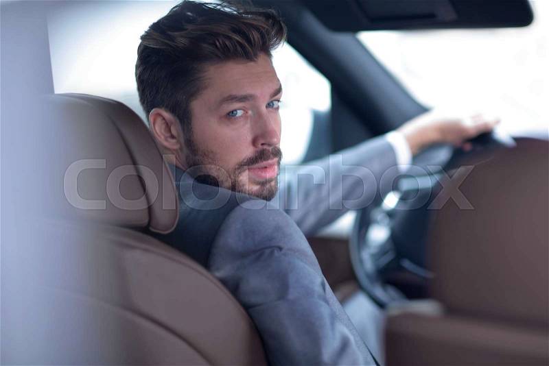 Successful man sitting behind the wheel of a prestigious car, stock photo
