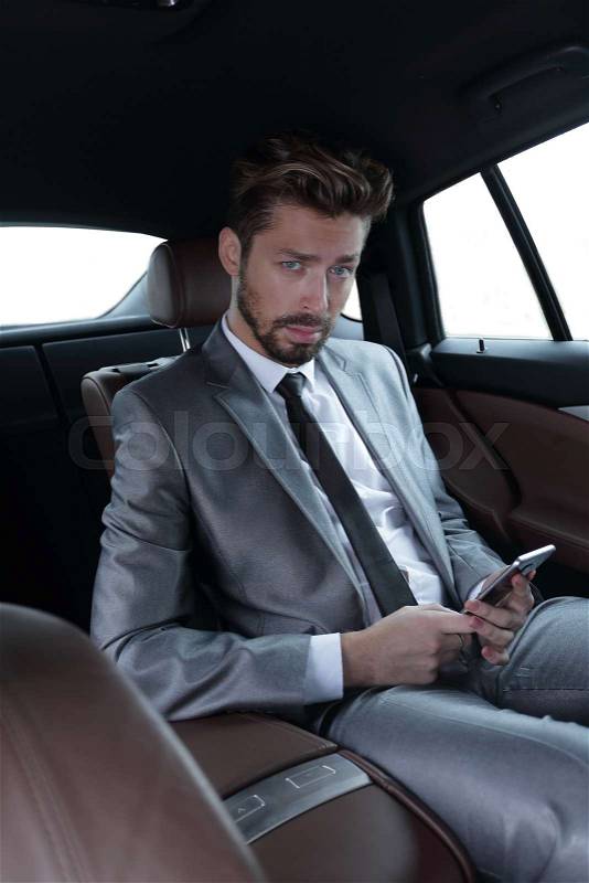 A businessman while traveling by car in the back seat, send a message or email and calls, stock photo