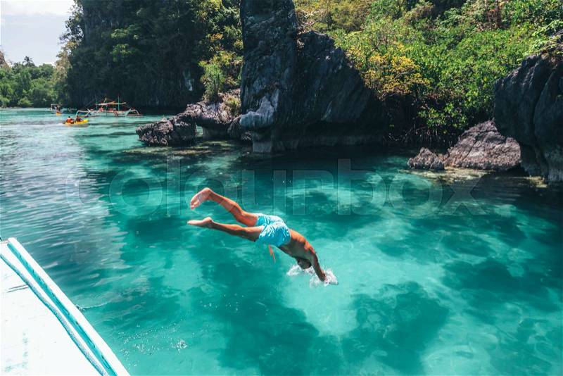 Man jumping into clear sea water in lagoon. Travelling tour in Asia: El Nido, Palawan, Philippines, stock photo