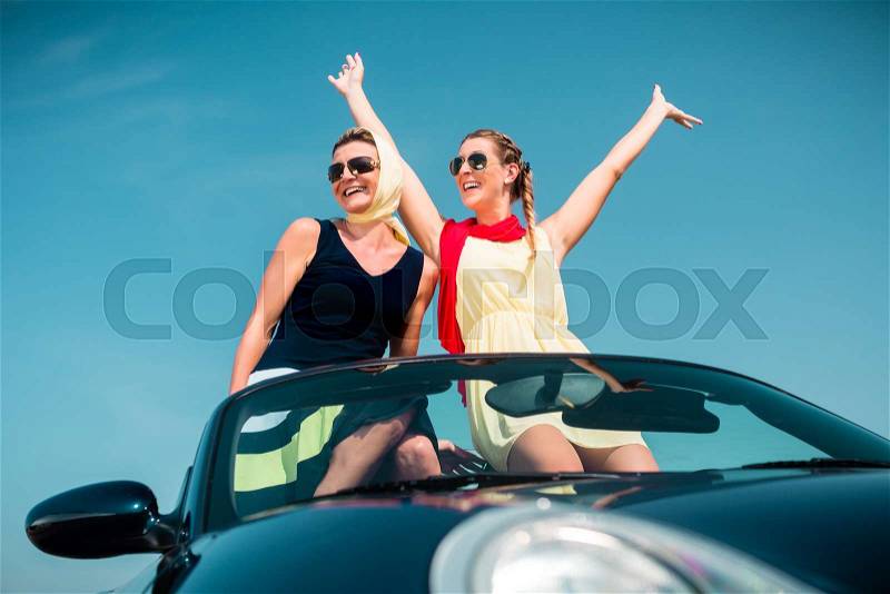 Woman having summer trip in convertible car stretching hands in the air with fun, stock photo