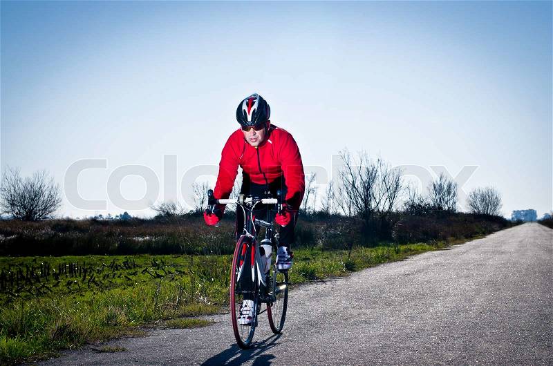 Man on road bike riding down open country road, stock photo
