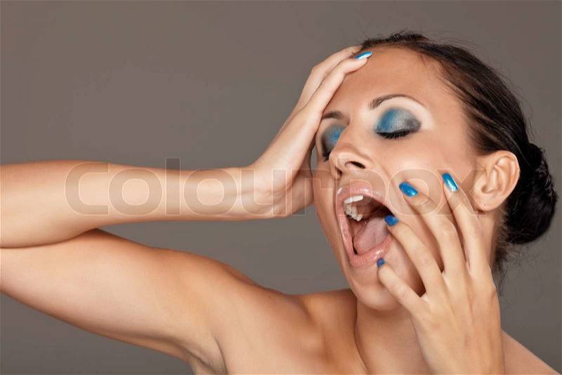 Young woman shouting on grey background, stock photo