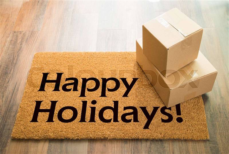 Happy Holidays Welcome Mat On Wood Floor With Shipment of Boxes, stock photo