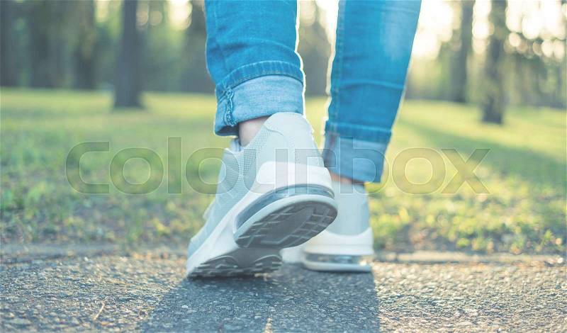 Walking in gray running shoes good for everyday wearing, blue jeans, back to camera, stock photo