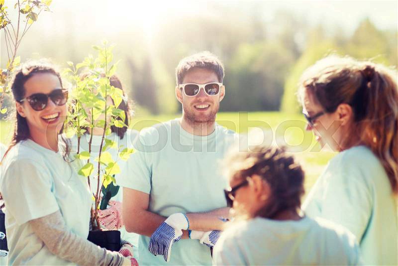 Volunteering, charity, people and ecology concept - group of volunteers planting trees in park, stock photo