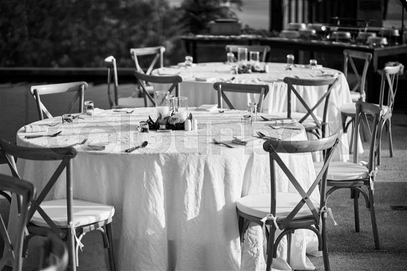 The Black and White of wedding reception dinner table setup, with the modern folding lawn chairs. The empty glass and place on the table, The candle and flowers use for decoration, stock photo