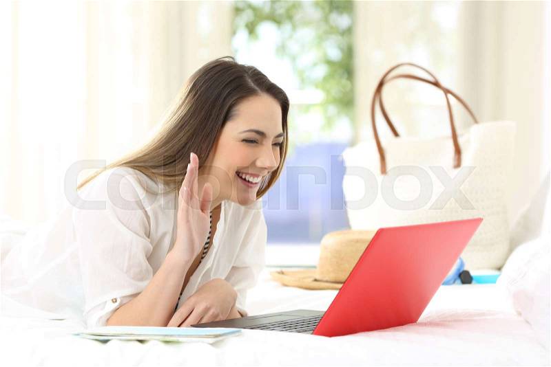 Happy hotel guest having a vide call in a room on summer vacations on the beach, stock photo