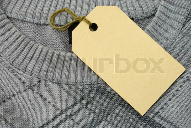 The label is attached to a sweater of gray color, stock photo