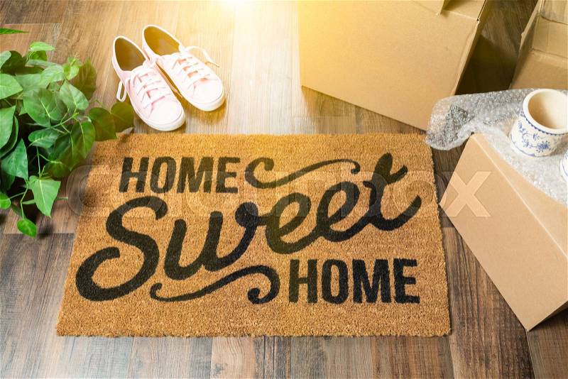 Home Sweet Home Welcome Mat, Moving Boxes, Pink Shoes and Plant on Hard Wood Floors, stock photo