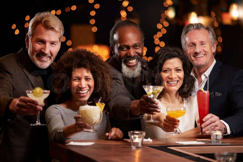 Portrait Of Middle Aged Friends Celebrating In Bar Together, stock photo