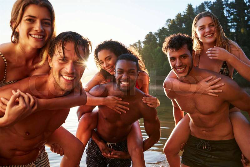 Three young adult couples piggy backing in a lake, close up, stock photo