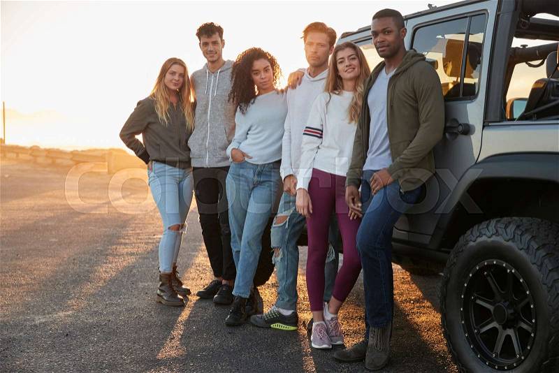 Young adult friends on a road trip standing by their jeep, stock photo