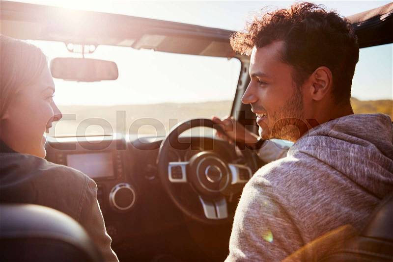 Happy couple driving in car with sunroof open, passenger POV, stock photo
