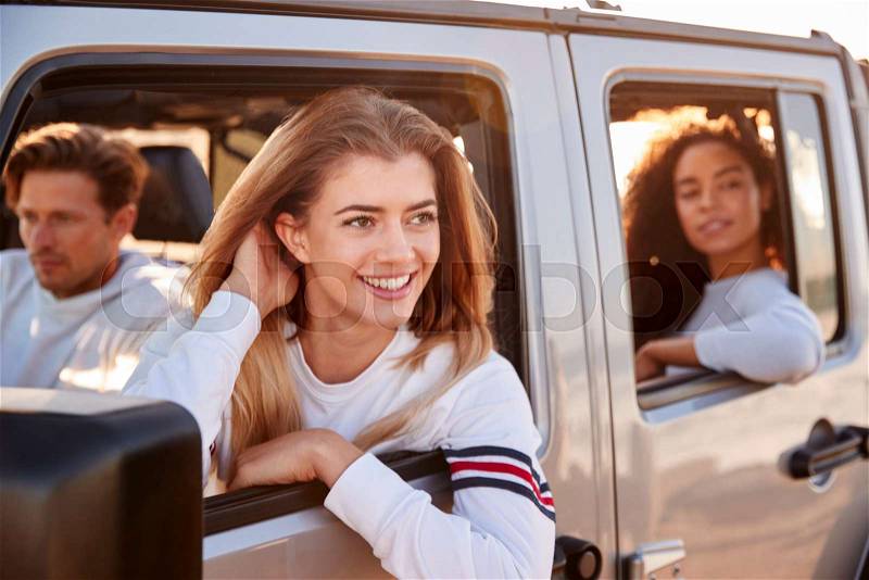 Young adult friends in a car looking out of open windows, stock photo