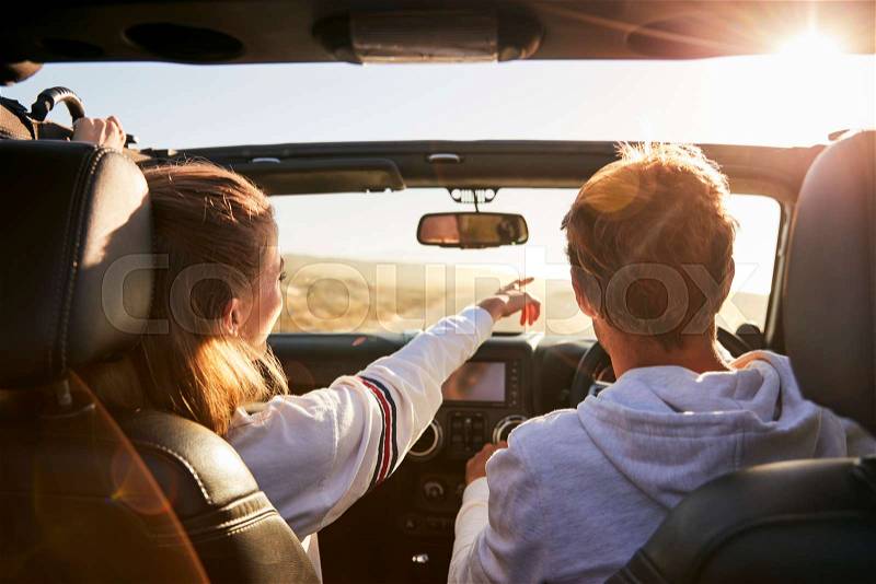 Young adult couple driving, woman pointing out directions, stock photo