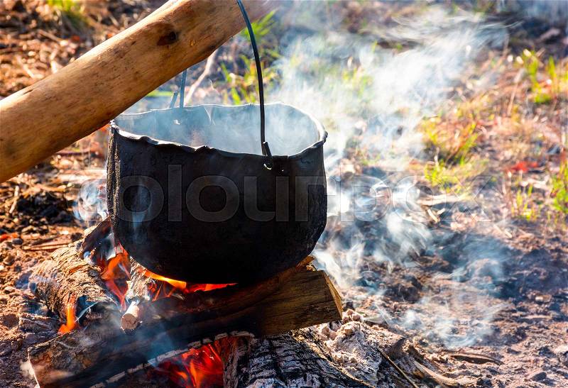 Cauldron in steam and smoke on open fire. outdoor cooking concept. old fashioned way to make food, stock photo