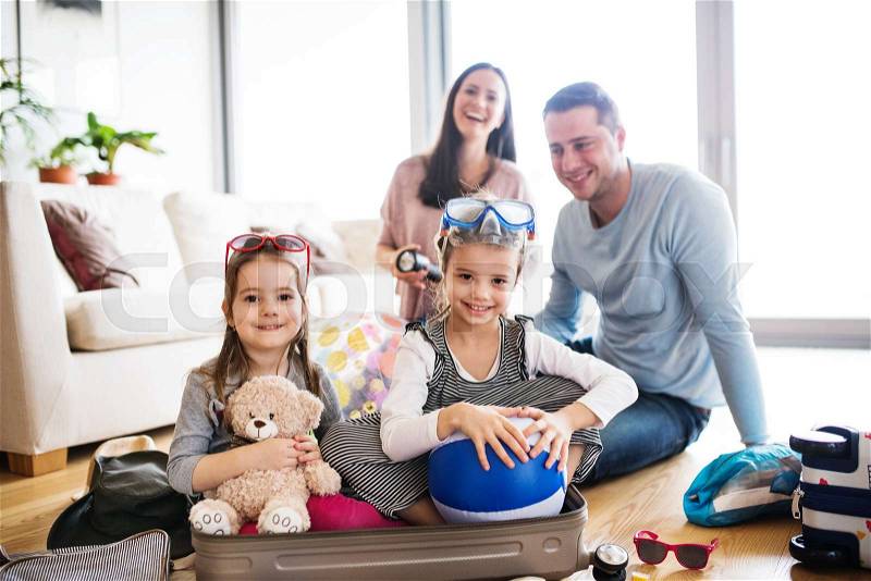Portrait of a young happy family with two children packing for holiday at home, stock photo
