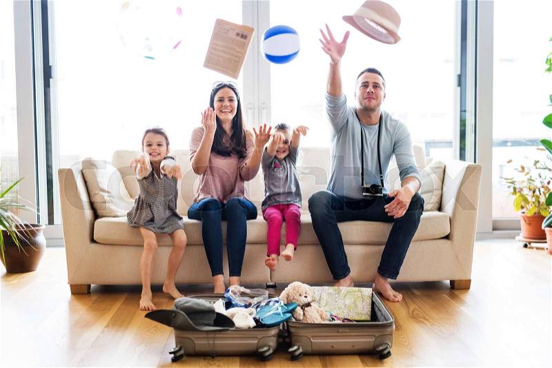 Portrait of a young happy family with two children packing for holiday at home, stock photo