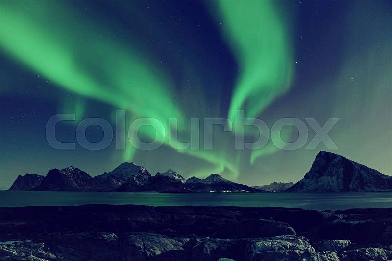 Northern Lights, Aurora Borealis shining green in night starry sky at winter Lofoten Islands, Norway, stock photo