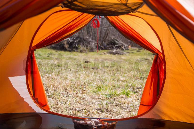 A look through the entrance of the tent. Orange camping tent in an early spring. Exit door, stock photo