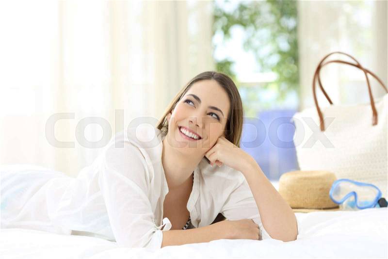 Hotel guest lying on the bed dreaming looking above on summer holidays, stock photo