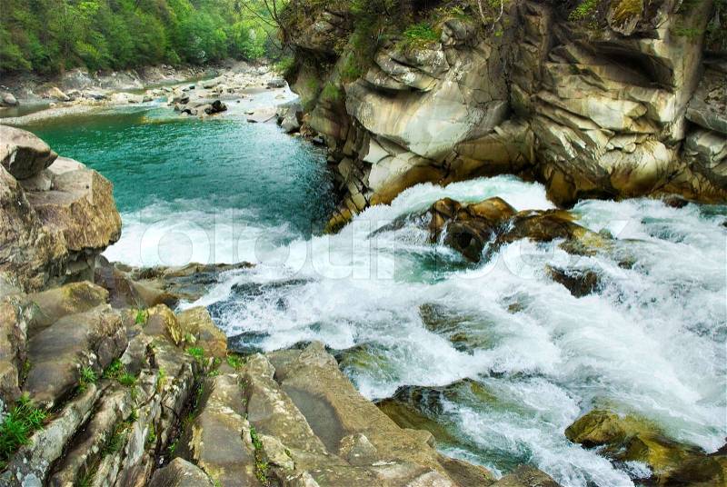 Waterfalls cascade between rocks in summer forest, stock photo