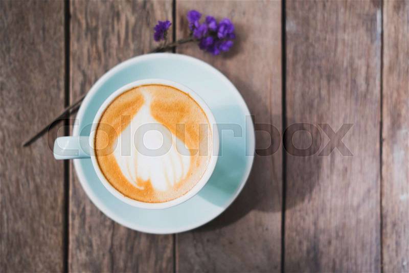 Top view of hot coffee in green cup with latte art on wooden plank table with forget me not flower,Food and drink concept,vintage filter, stock photo