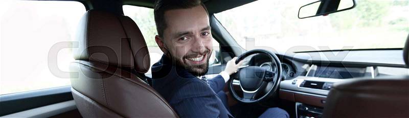 Successful man sitting behind the wheel of a prestigious car, stock photo