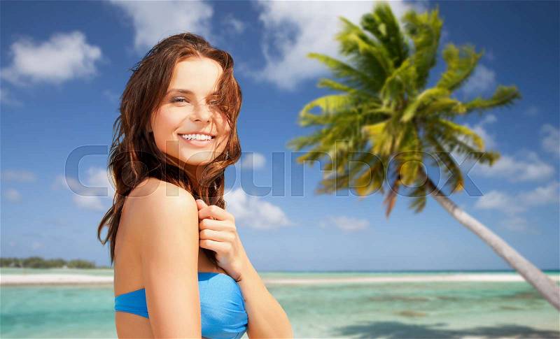 Summer holidays, vacation and travel concept - happy young woman posing in bikini swimsuit over exotic tropical beach with palm tree background in french polynesia, stock photo