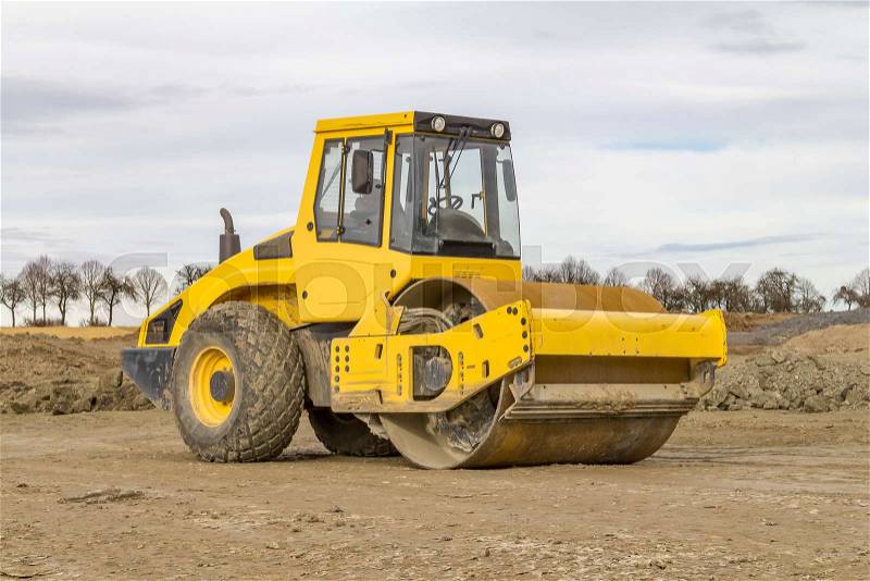 Yellow road roller at a loamy construction site, stock photo