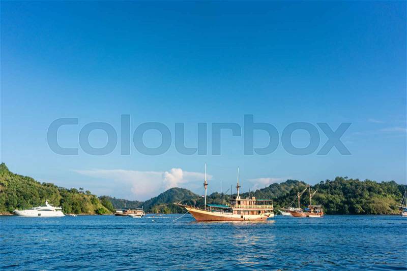 Idyllic seascape with sailing boats moored along the shore in a sunny day of summer in Flores Island, Indonesia, stock photo
