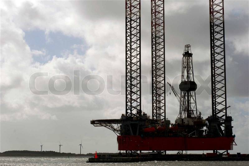 Closeup of ocean oil rig docked in Esbjerg harbor Danish island Fanoe with windmills can be seen in the background, stock photo