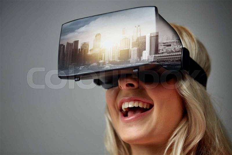 Technology, augmented reality, entertainment and people concept - happy young woman with virtual headset or 3d glasses playing video game with singapore city on screen over gray background, stock photo