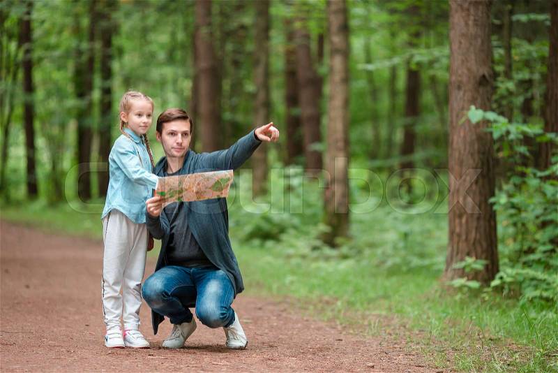 Young father and little girl biking at summer warm day and finding the way by the map, stock photo