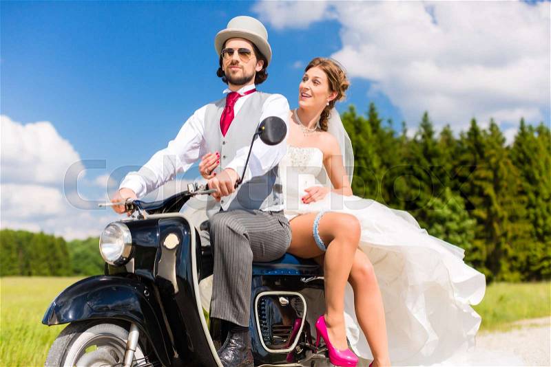 Wedding concept, bride and groom on motor scooter, she is showing her garter on leg, stock photo