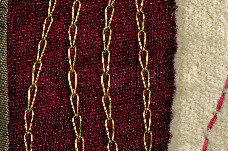 A red cloth texture with strong contrast and lines with golden decorative chains, stock photo