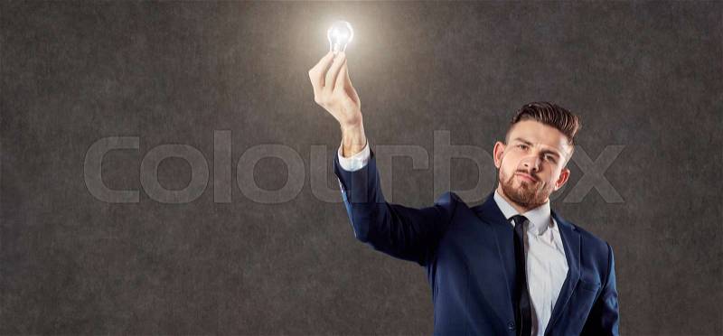 Businessman with luminous light bulb in hand on copyspase background. , stock photo