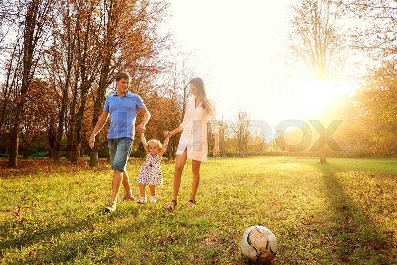 Family playing in the park in sun at sunset, stock photo