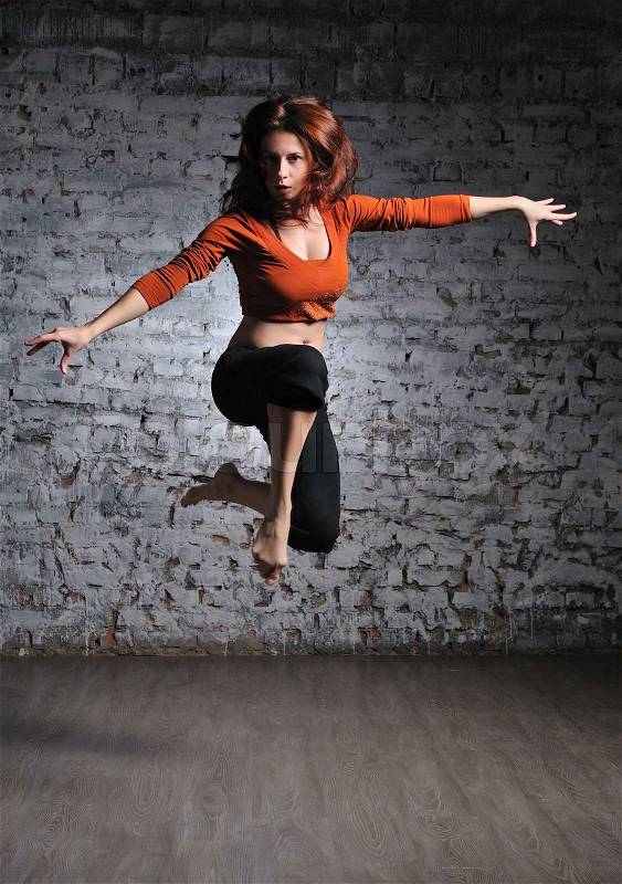 Girl in sportswear jumping on the brick wall background, stock photo