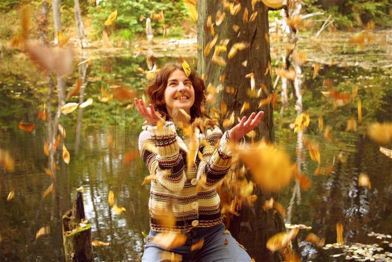Girl throws up the leaves in autumn forest, stock photo