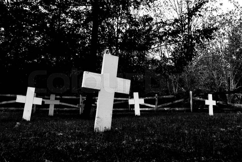 Indian cemetery abstract showing tilted white crosses and a dark spooky tree and fence, stock photo