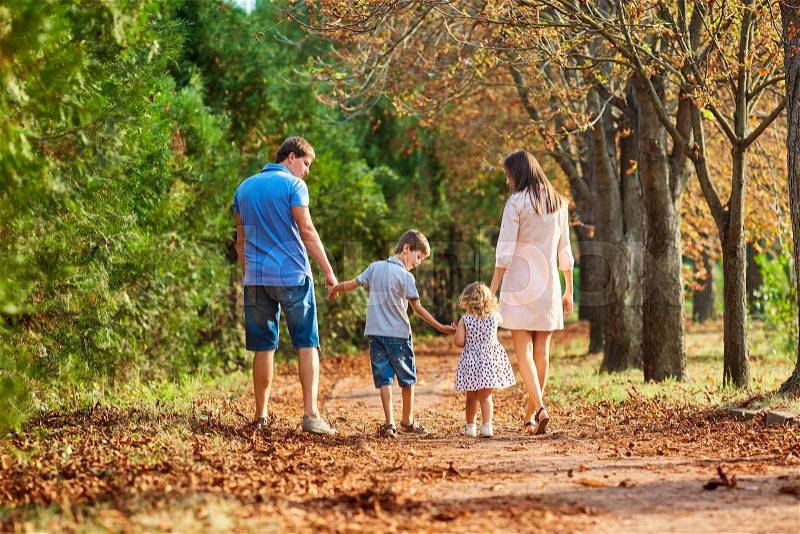 The family in the park. Happy parents with children walk in the nature in the evening at sunset, stock photo