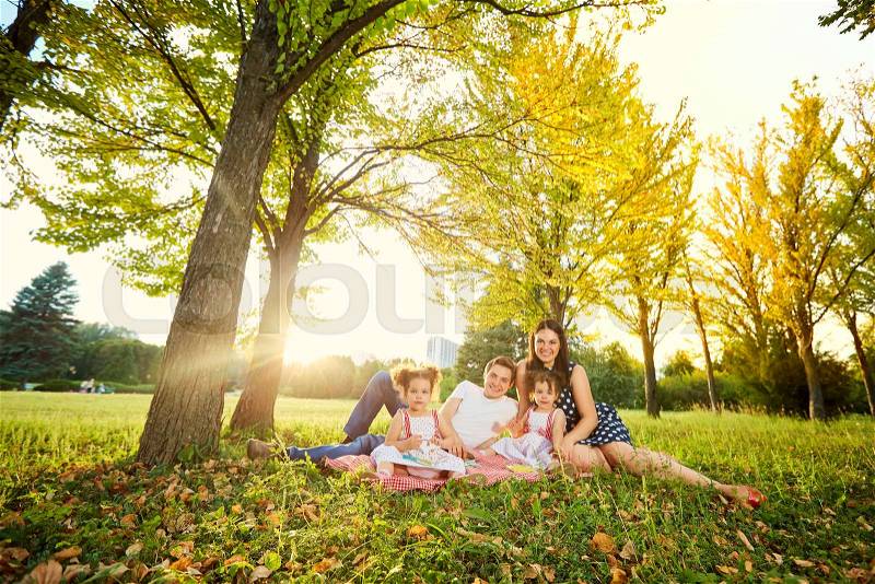 The family in the park. Happy parents with children walk in the nature in the evening at sunset, stock photo