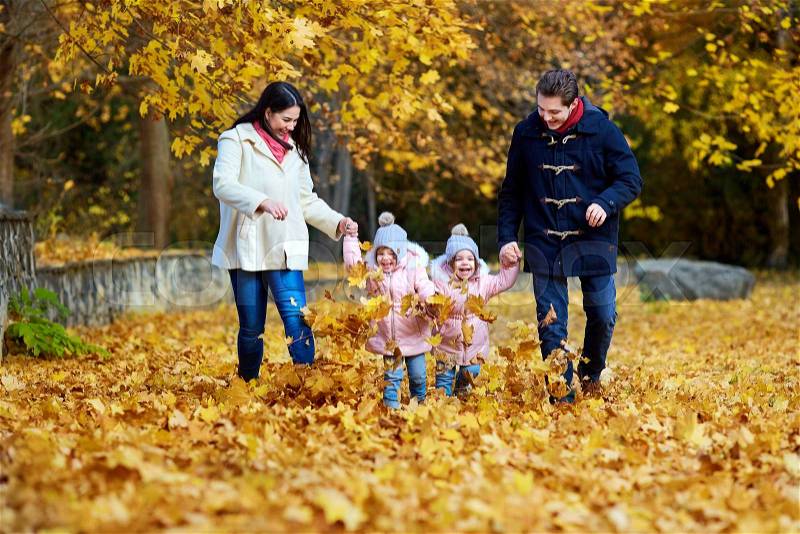 Happy family in autumn park. Mother, father and two little girls on the nature running, playing, laughing. The concept of a happy family, stock photo