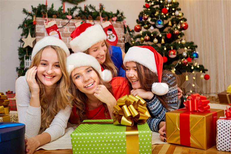 Friends at Christmas. Beautiful girl laughing and smiling with gifts in the room with decor and Christmas tree in the new year, stock photo