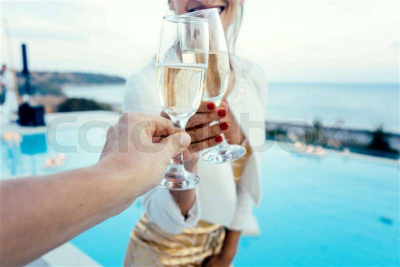 Woman and man clinking glasses at elegant pool party in summer, stock photo