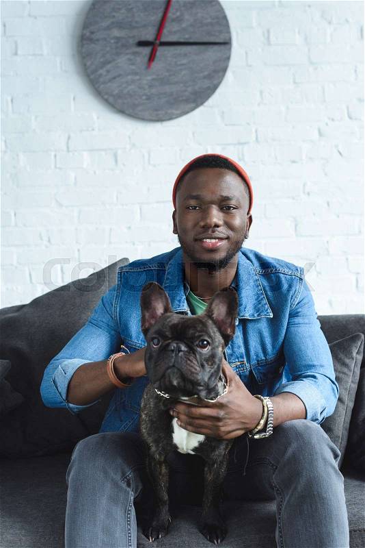 Young man with French bulldog sitting on sofa, stock photo