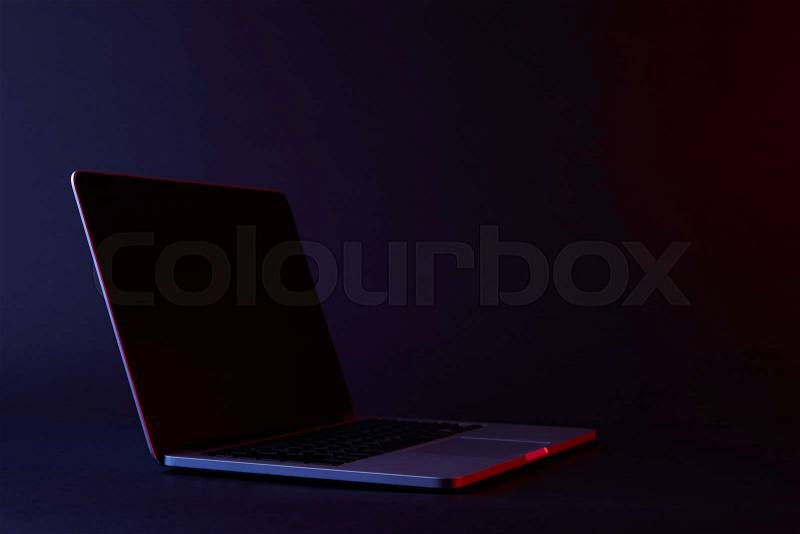 One turned off laptop with reflecting screen on dark, stock photo