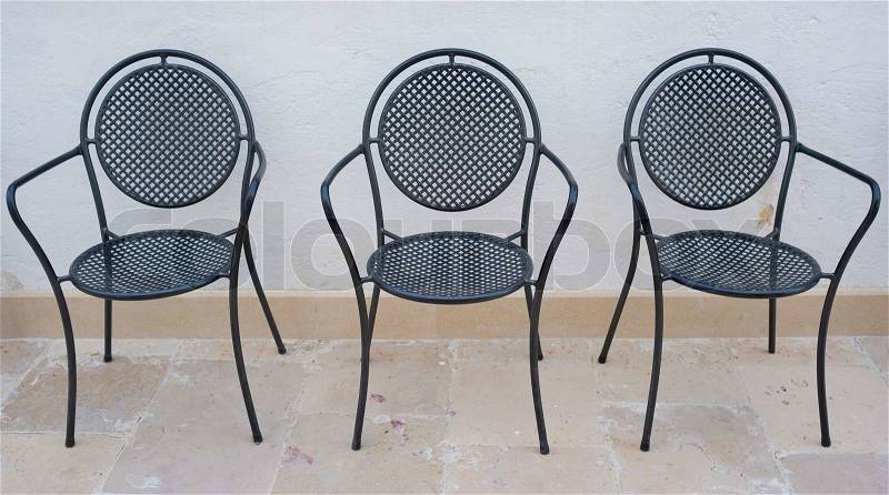 Four empty garden chairs in Italian patio on a hot day, stock photo