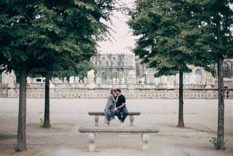 Beautiful stylish young couple hugging and kissing on bench in Dresden, Germany , stock photo
